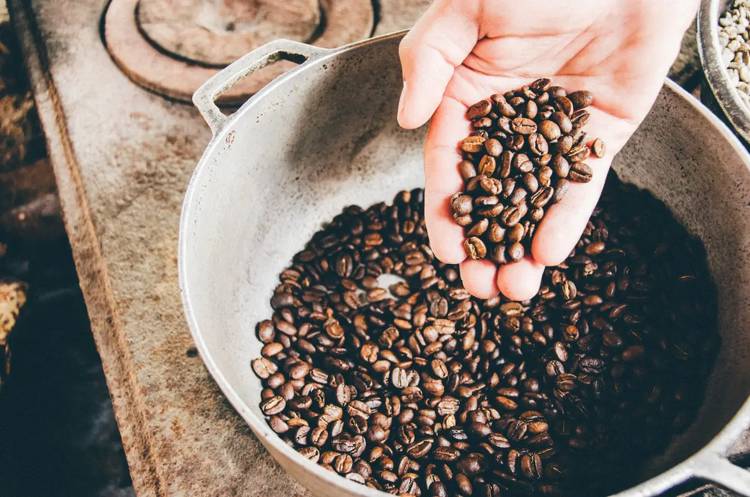 a person is pouring coffee beans into a pot