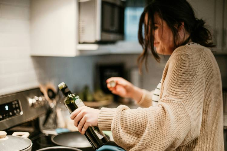 a woman is pouring olive oil into a frying pan