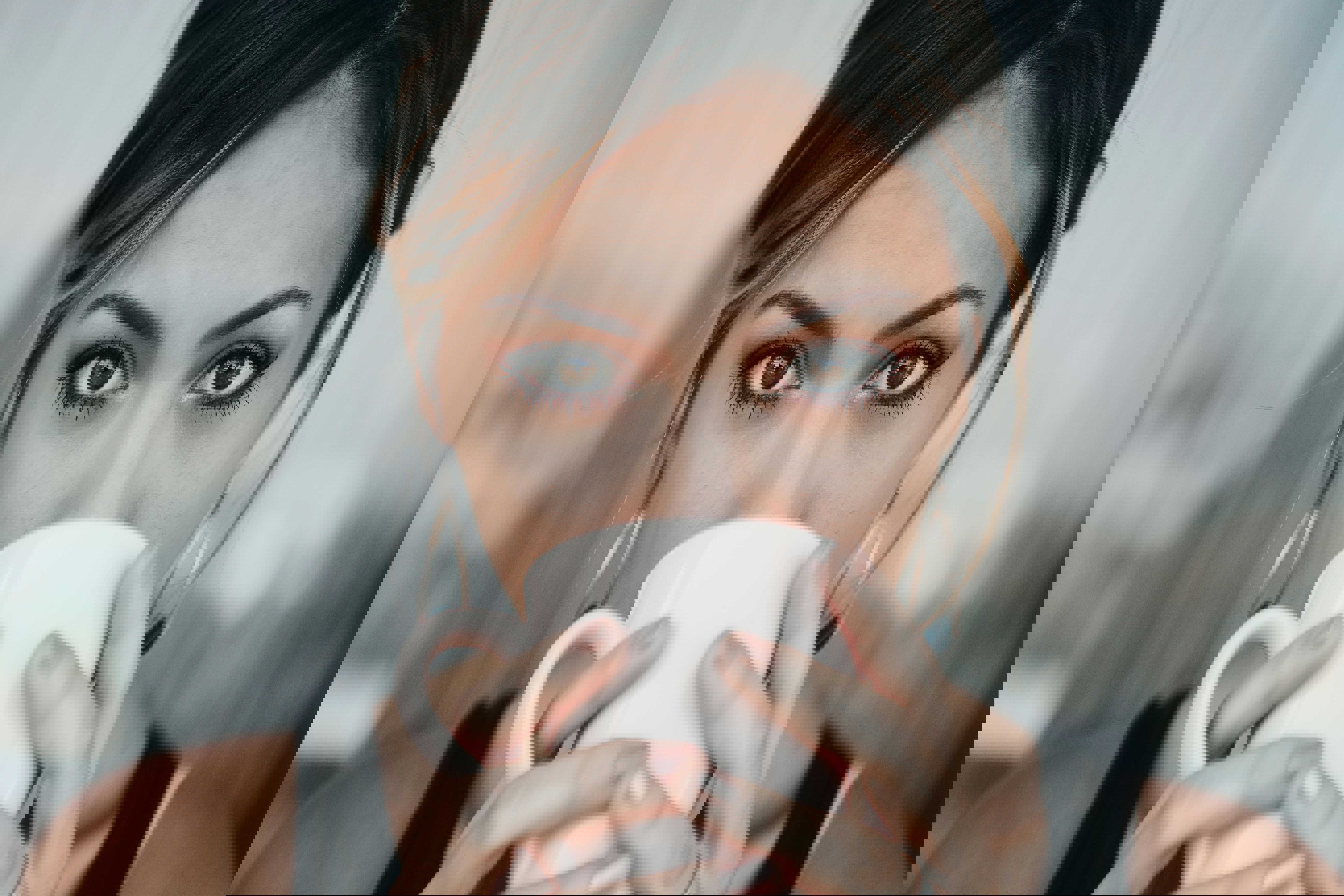 a woman drinking from a pink cup with her eyes closed