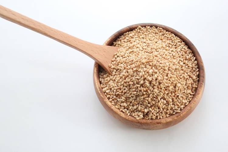 sesame seeds in a wooden bowl with a wooden spoon