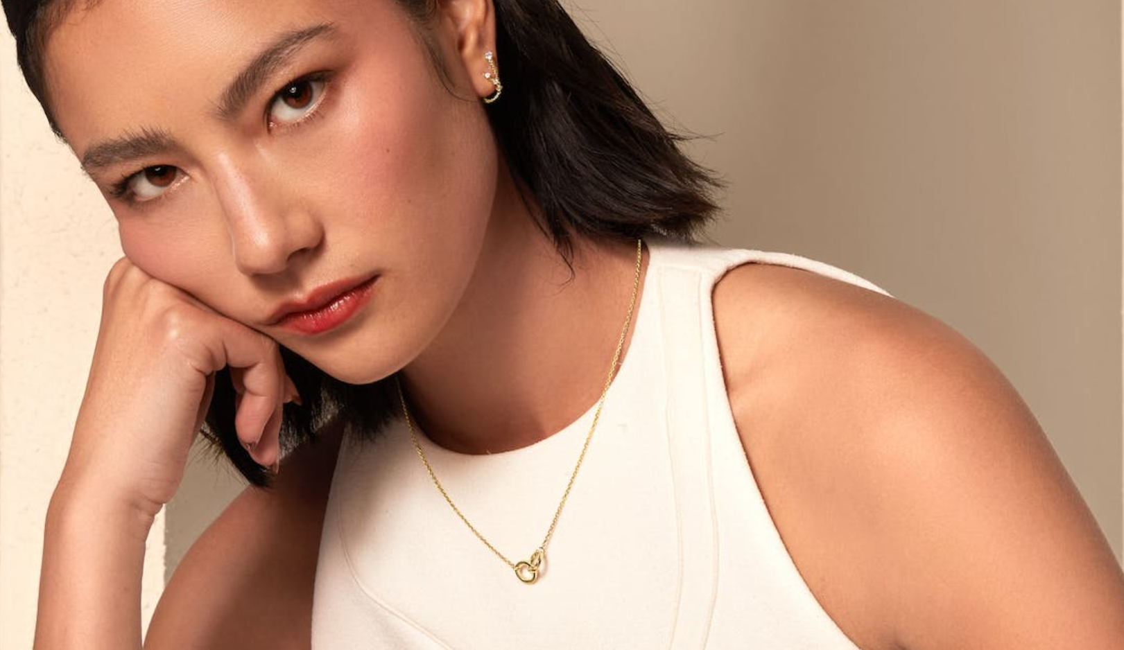 a woman wearing a white tank top and a gold necklace