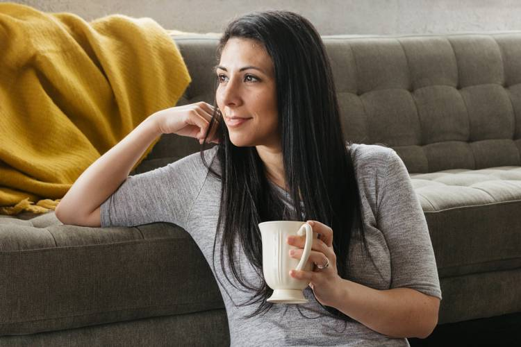a woman sitting on a couch holding a cup of coffee