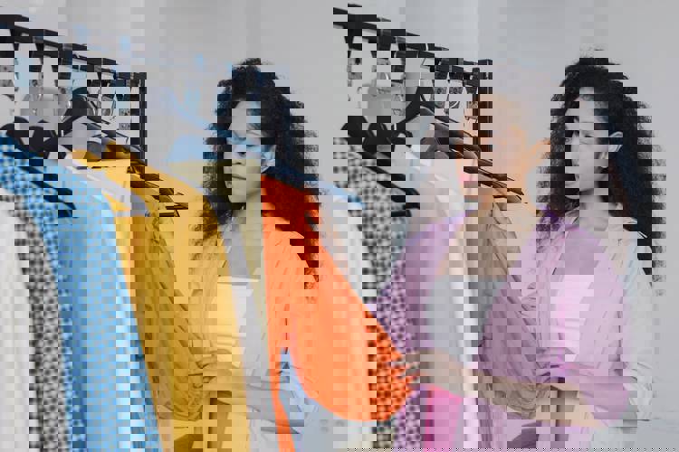 a woman in a pink shirt is looking at clothes on a rack