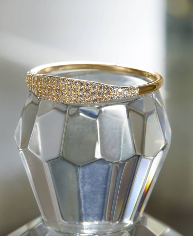 a gold ring is sitting on top of a clear glass container