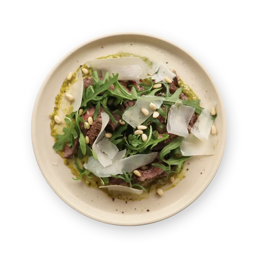 a plate of food with meat , vegetables and pine nuts on a black background