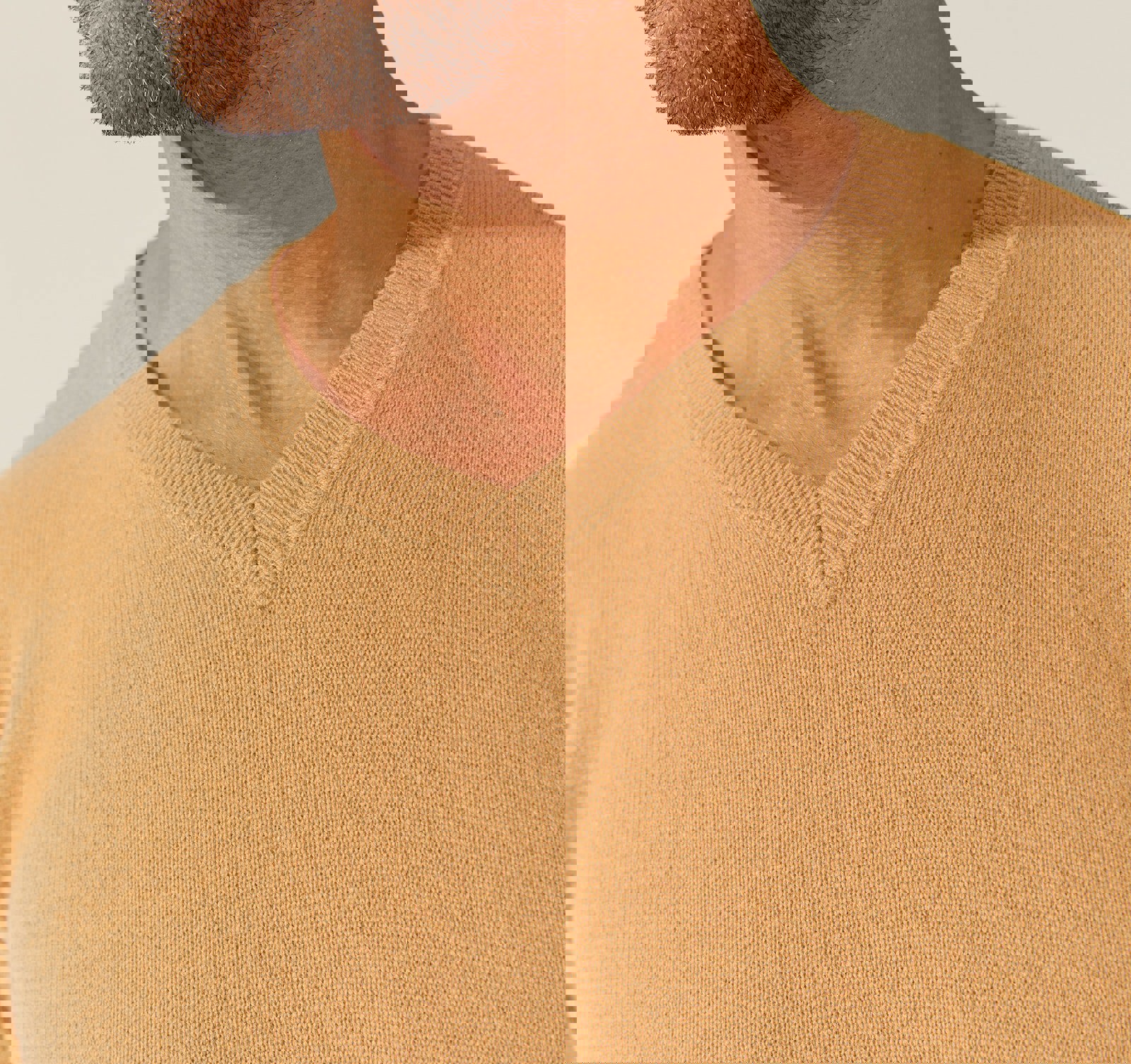 a man wearing a tan sweater with a v-neck