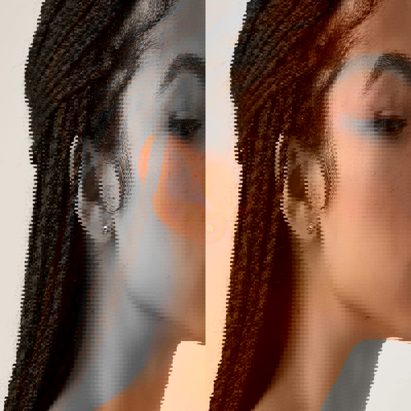 a close up of a woman 's ear with braids and earrings