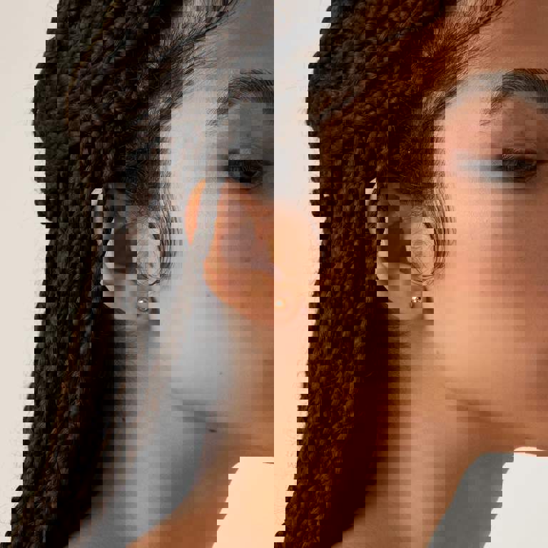 a close up of a woman 's ear with braids and earrings