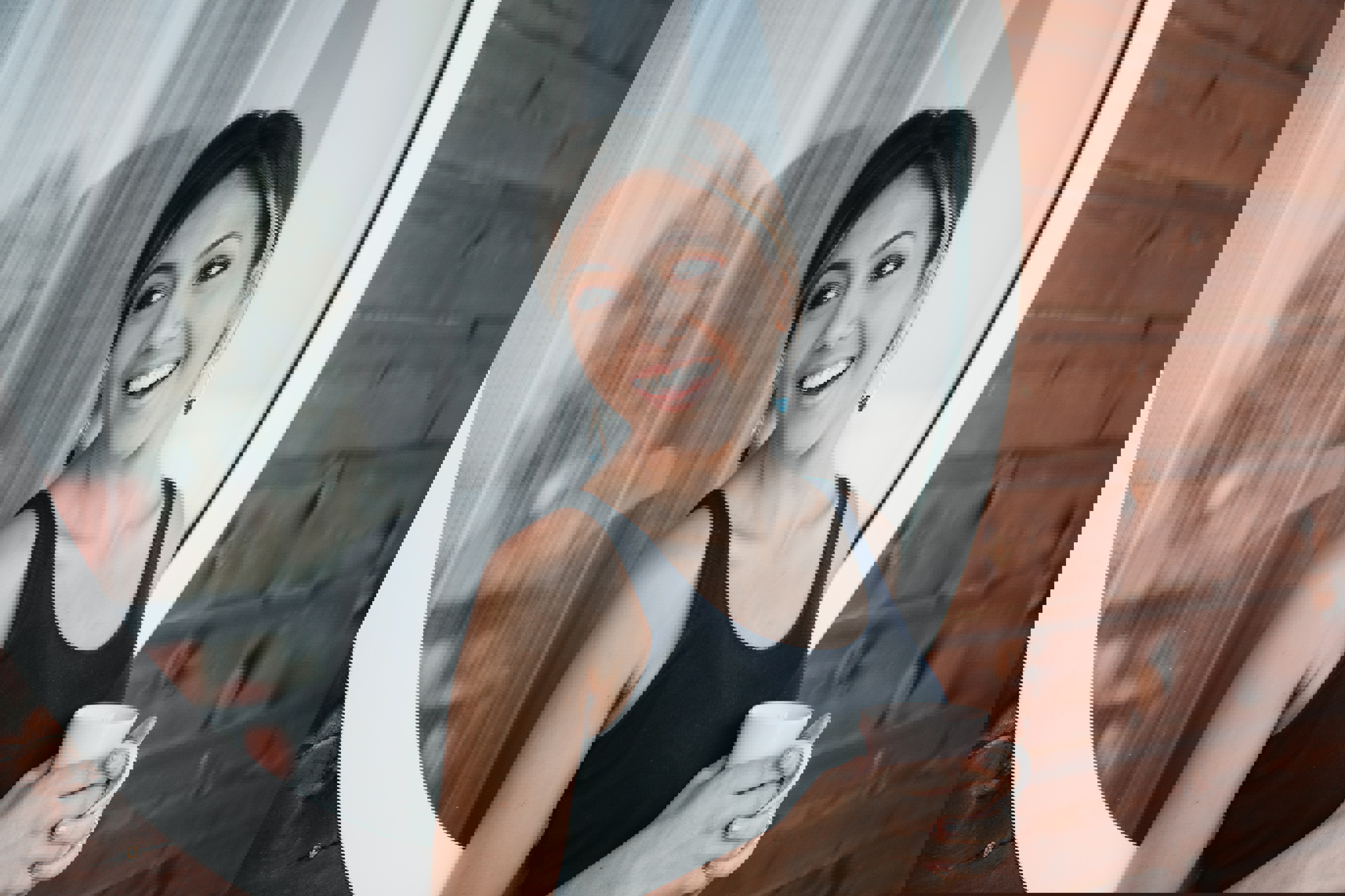 a woman holding a cup in front of a round window