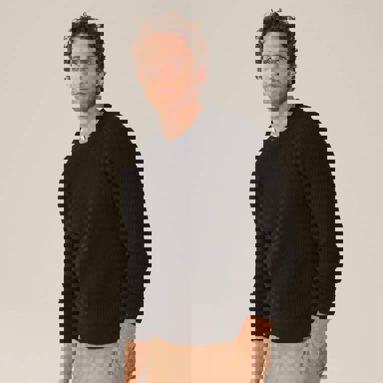 a man wearing a black sweater has his hands in his pockets