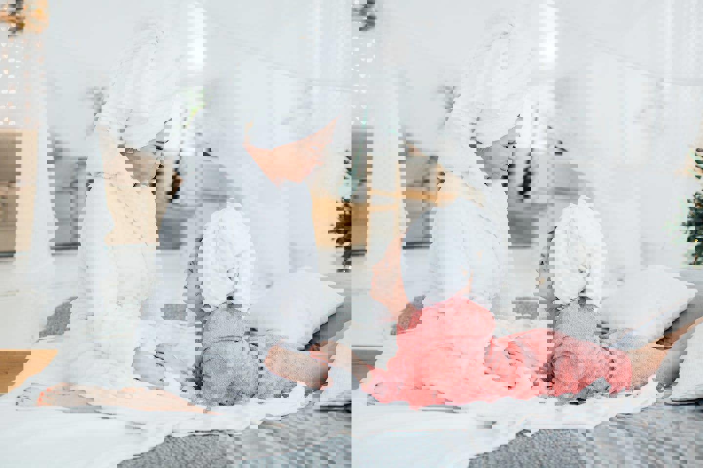 a woman and a little girl are sitting on a bed with towels wrapped around their heads