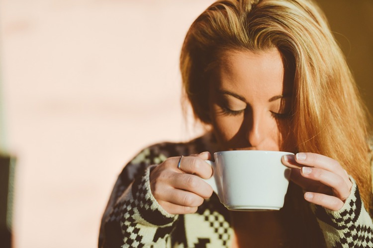 a woman drinking a cup of coffee with her eyes closed