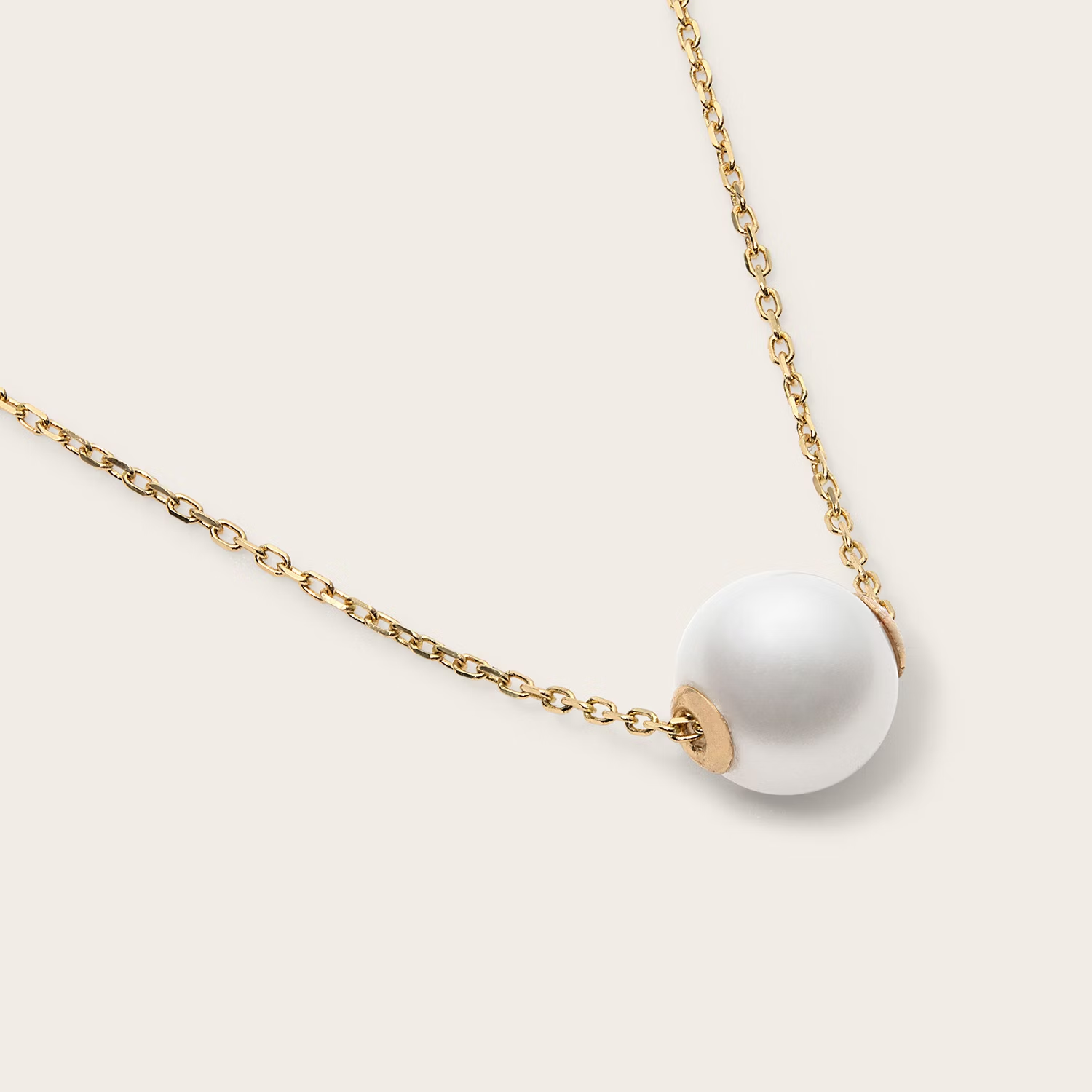 a close up of a necklace with a pearl on a gold chain