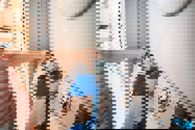 a woman is pouring detergent into a washing machine