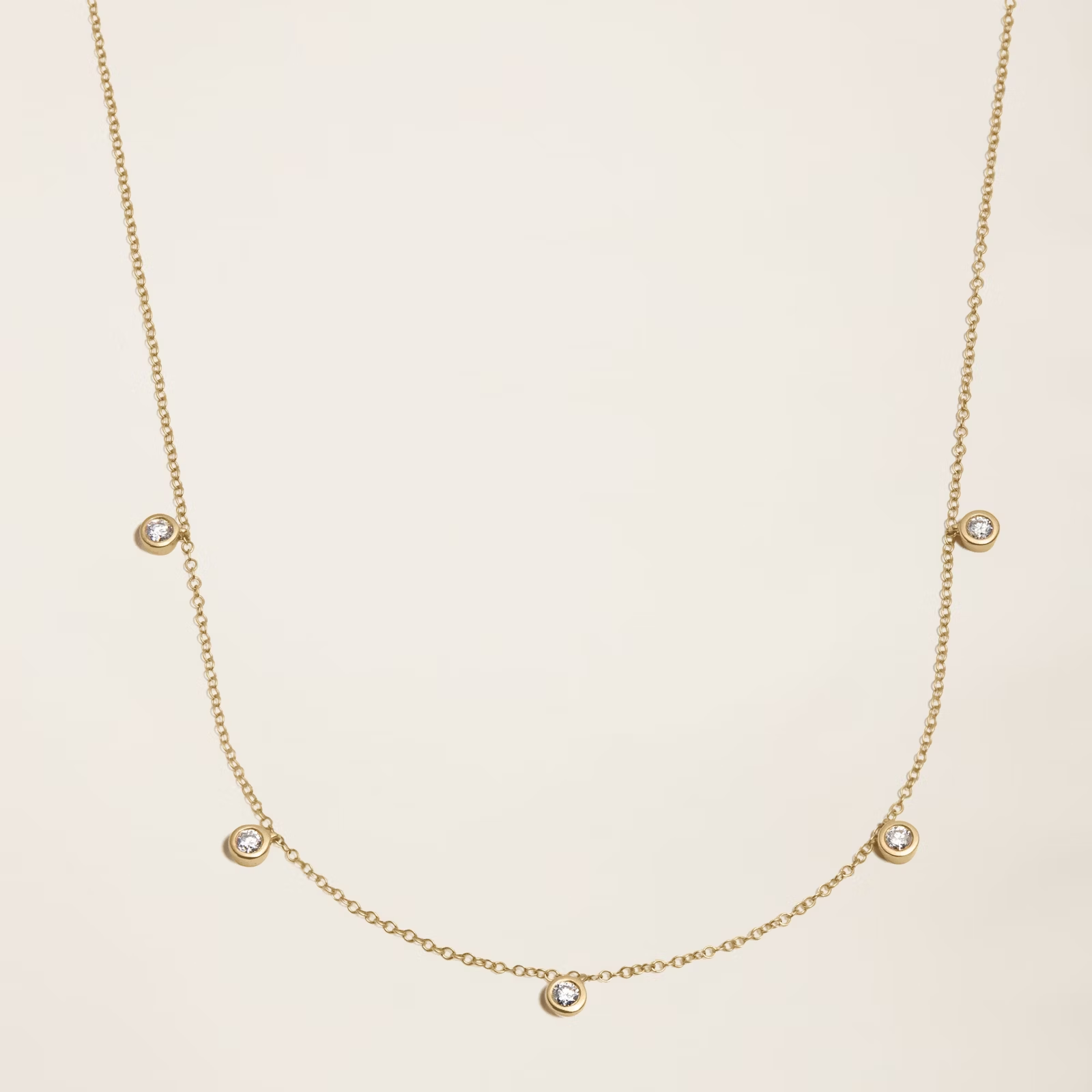 a gold necklace with diamonds on a chain on a white surface