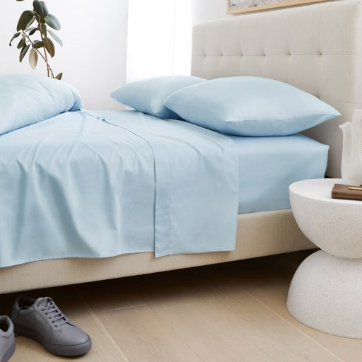 a bed with light blue sheets and pillows on it