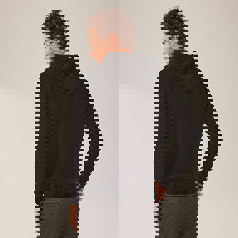 a man is wearing a black hoodie and grey sweatpants
