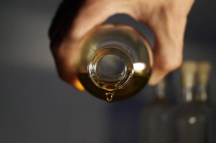 a hand is holding a bottle with a drop of oil coming out of it