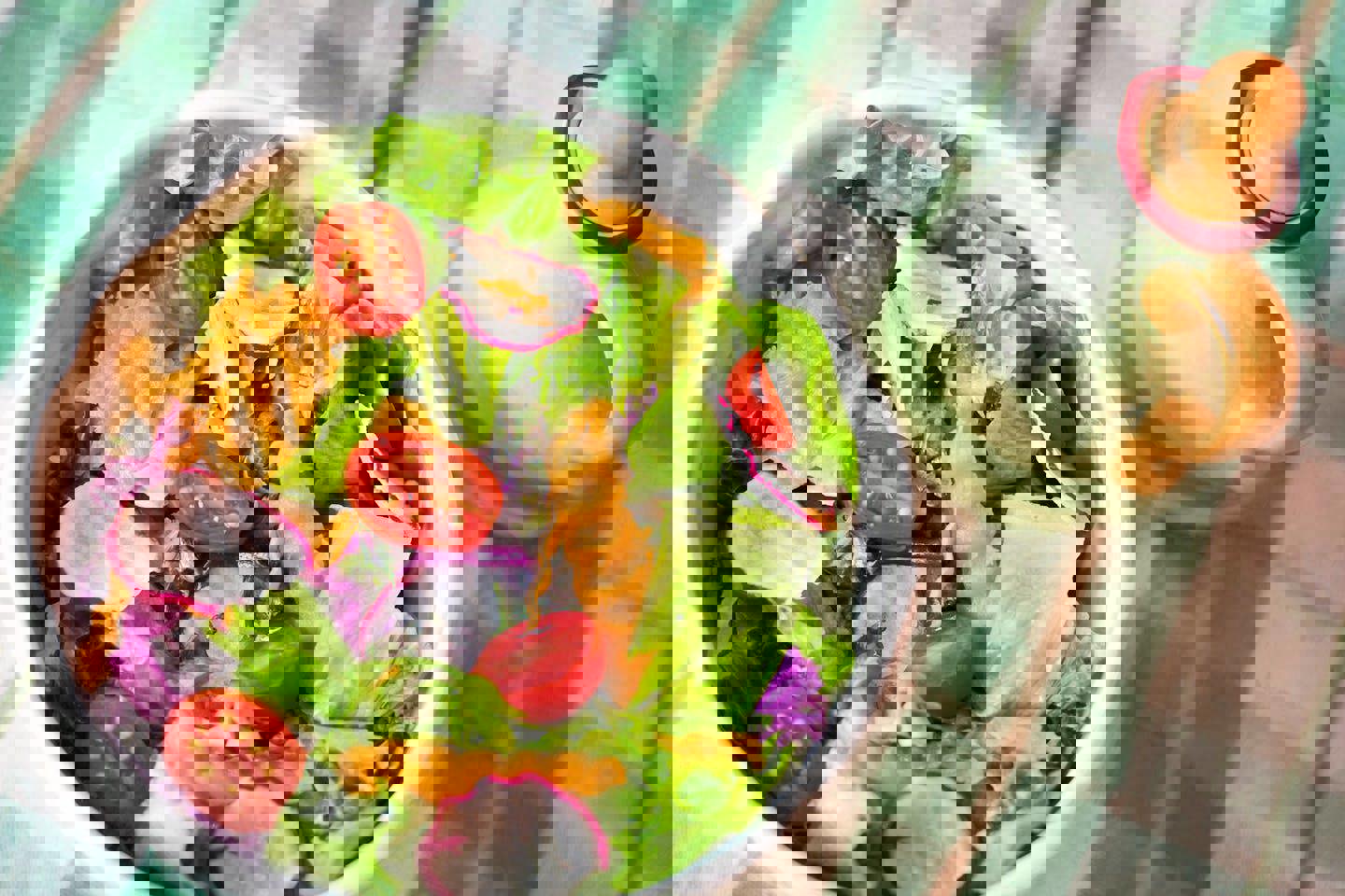 a bowl of salad with tomatoes , lettuce , carrots and radishes