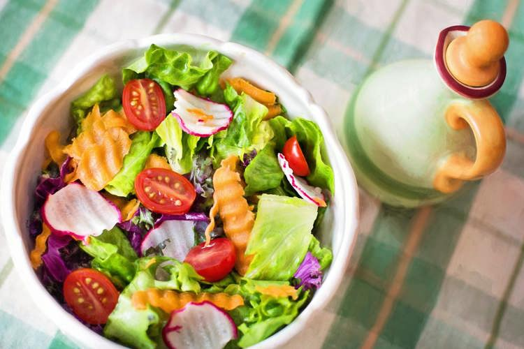 a bowl of salad with tomatoes , lettuce , carrots and radishes