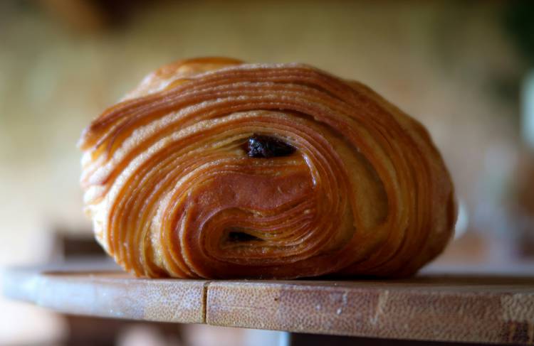 a close up of a chocolate croissant on a wooden cutting board