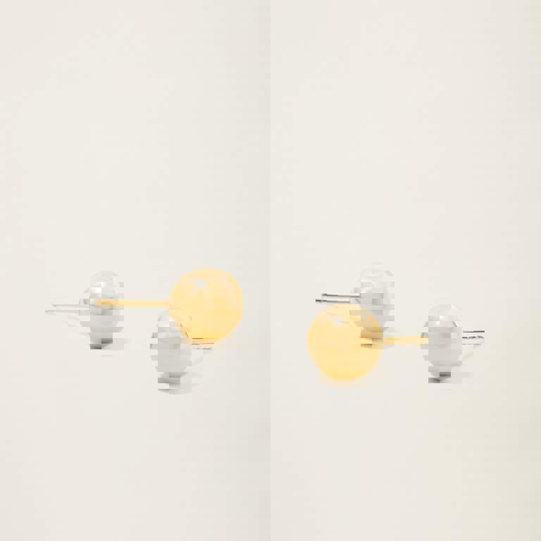 a pair of gold stud earrings on a white surface