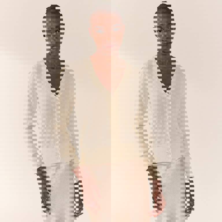 a woman wearing a white cardigan and a beige skirt