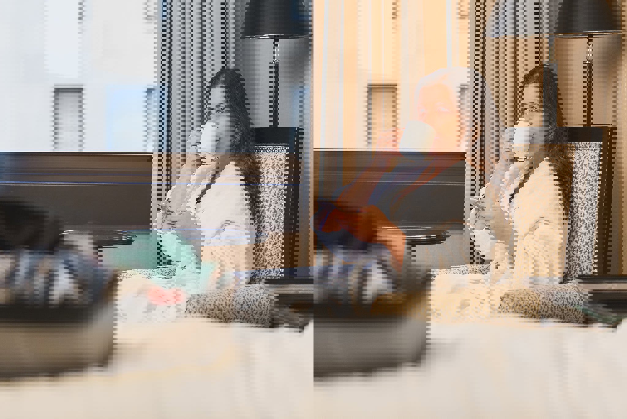 a woman sitting in a chair drinking a cup of coffee