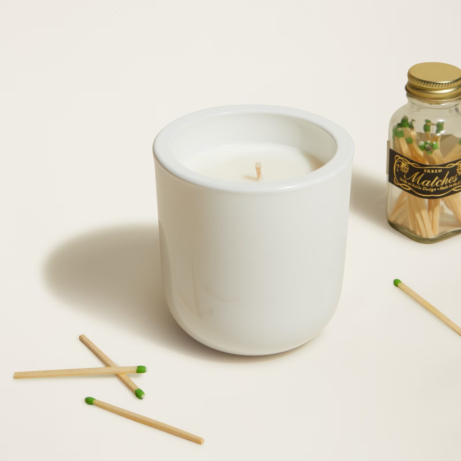 a bottle of matches sits next to a white candle