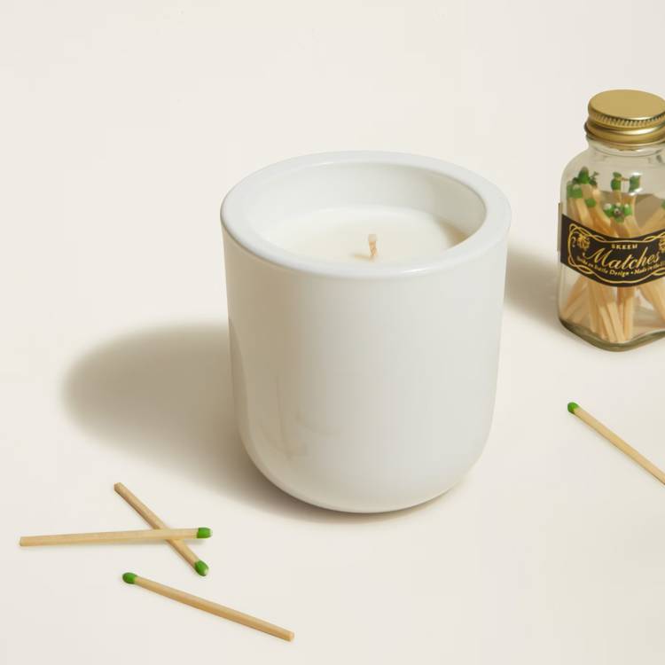 a bottle of matches sits next to a white candle