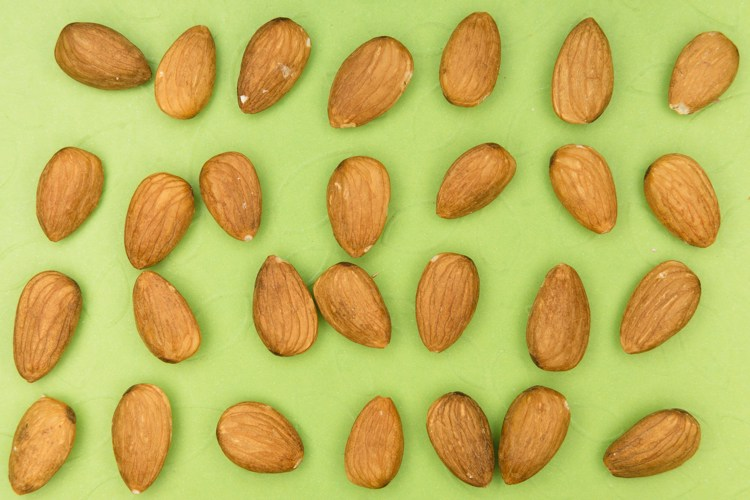 almonds are arranged in rows on a green surface