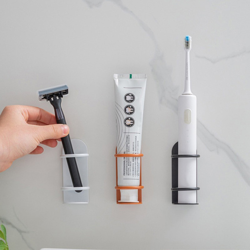 a person holding a razor next to a tube of toothpaste and an electric toothbrush