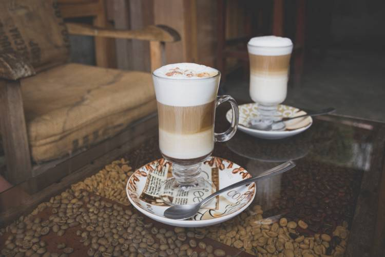 two glasses of latte on a saucer with the word coffee on it