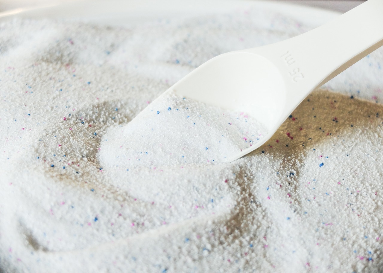 a measuring spoon is sitting on top of a pile of laundry powder