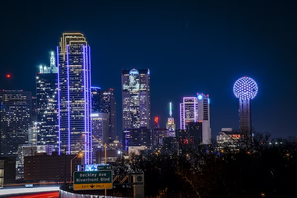 a city skyline lit up at night with a highway in the foreground