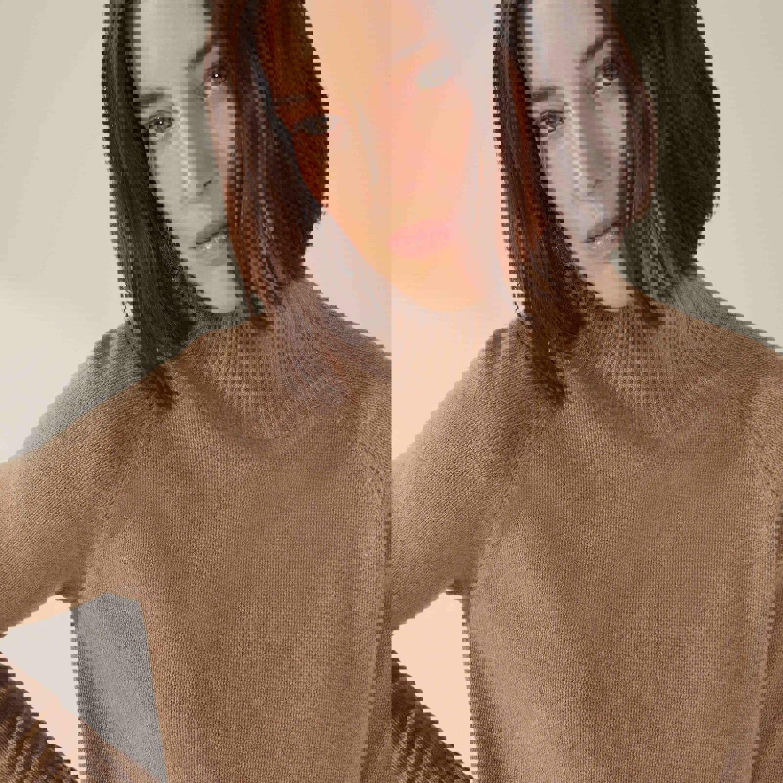 a woman wearing a brown sweater with a turtleneck