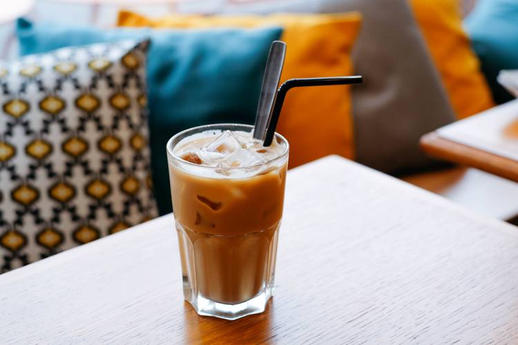 a glass of iced coffee with a straw on a table