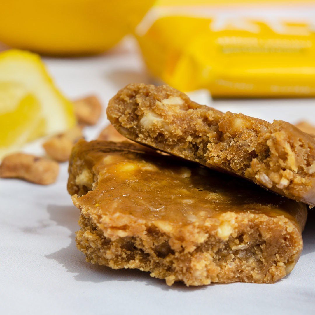 an unwrapped protein bar is stacked on a table with sliced lemons in the background