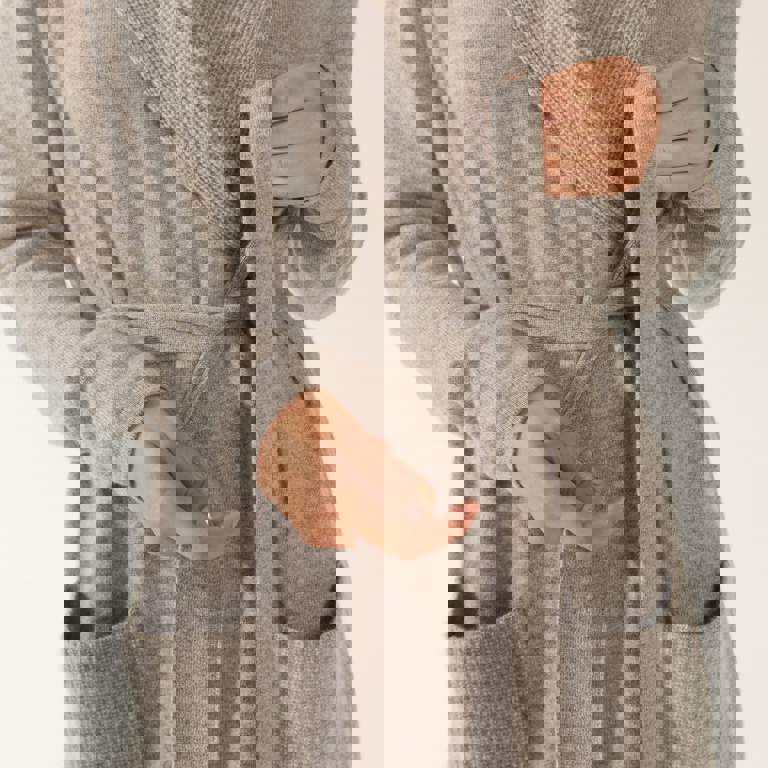 a woman wearing a grey robe with a belt around her waist