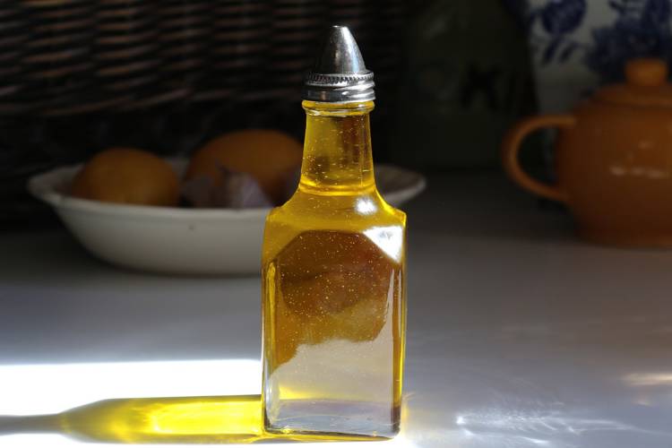 a bottle of oil sits on a table next to a bowl of lemons