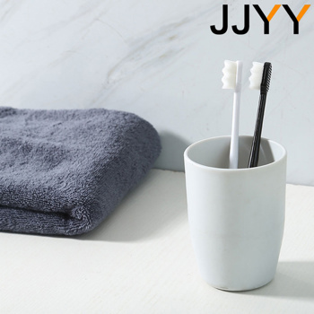 two toothbrushes in a jjyy cup next to a towel