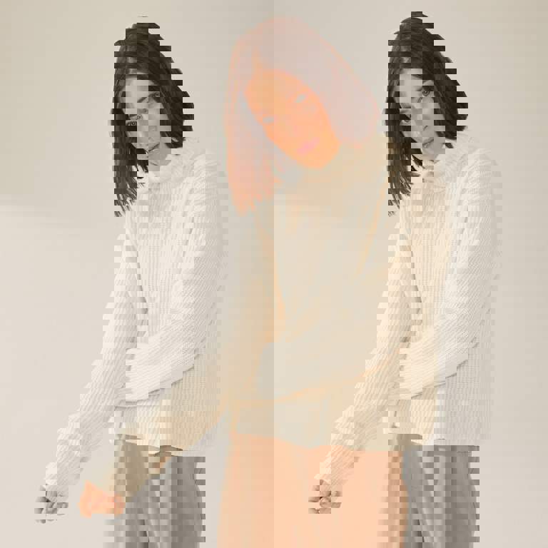 a woman wearing a white sweater and brown pants