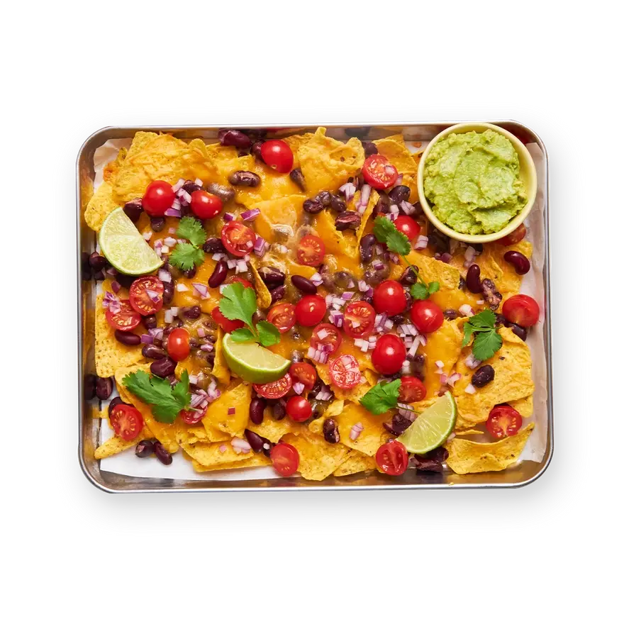 a tray of nachos with guacamole and tomatoes on a black background