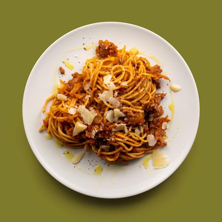 a white plate topped with spaghetti and meat sauce on a green background