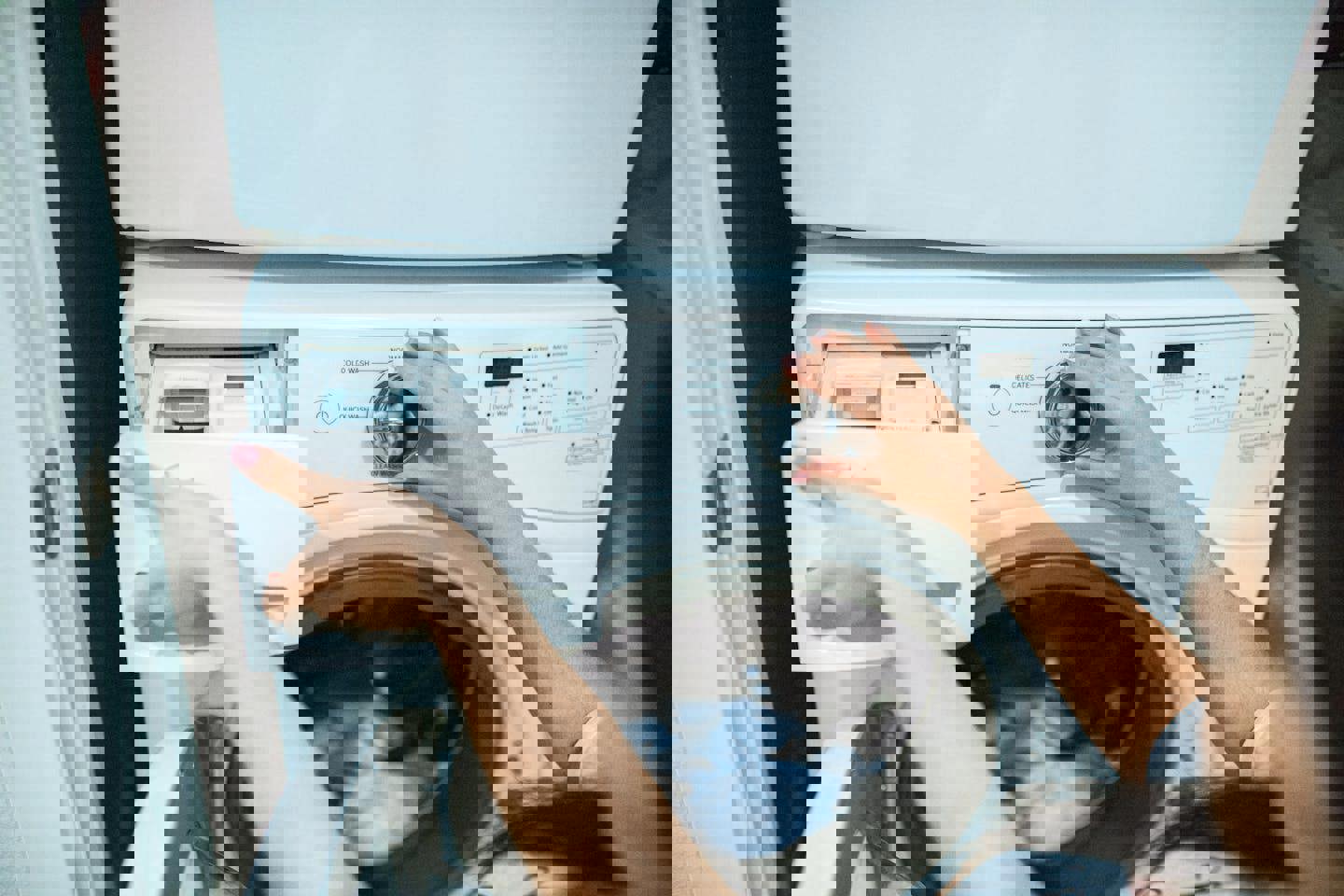 a woman is loading clothes into a washing machine