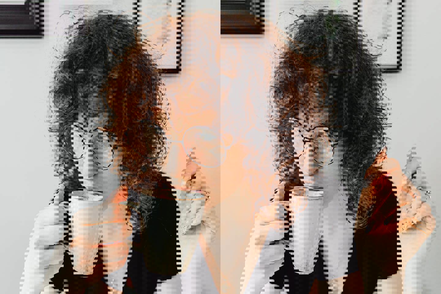 a woman with curly hair is drinking a cup of coffee