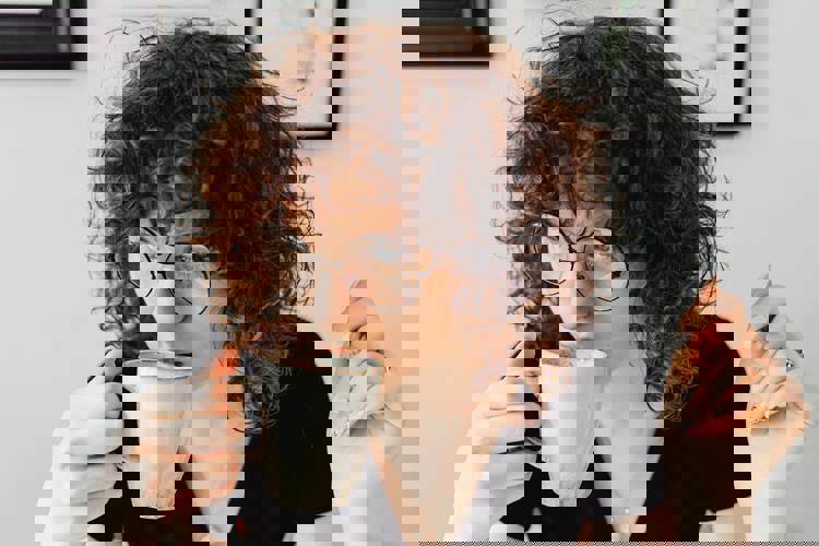 Woman drinks coffee a woman with curly hair is drinking a cup of coffee