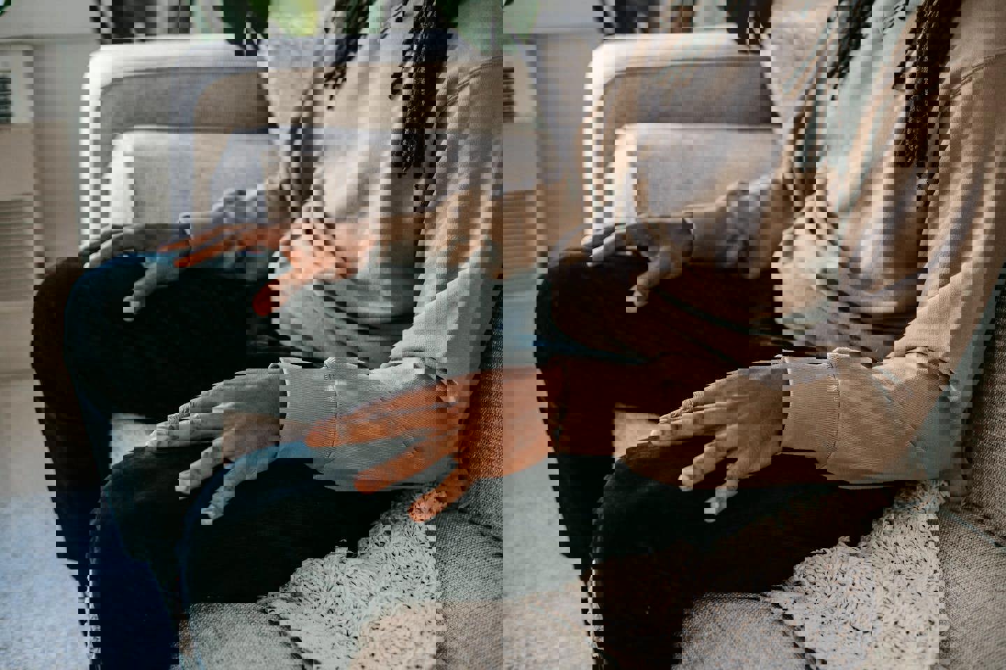 a man with dreadlocks is sitting on a couch with his hands folded