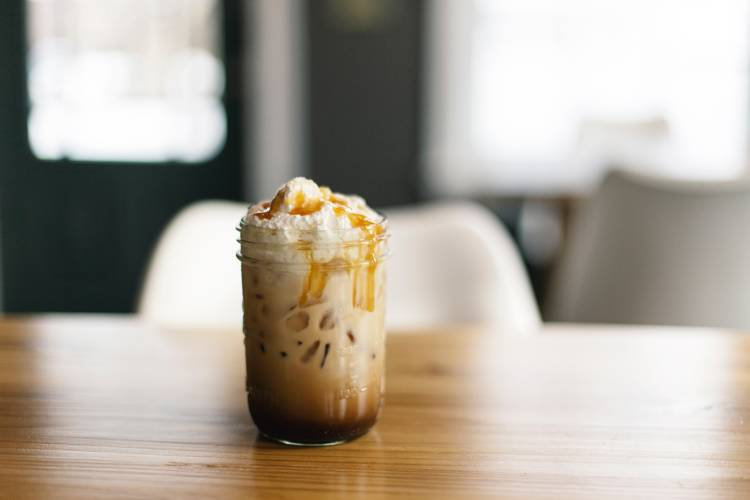 a glass of iced coffee with whipped cream and caramel on top