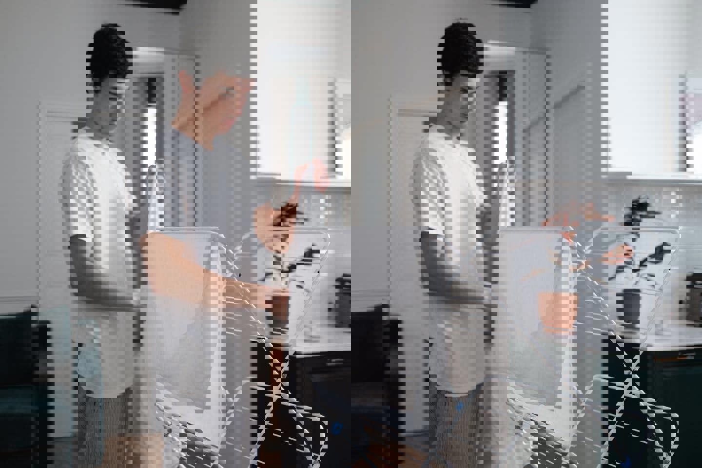 a man is hanging clothes on a drying rack in a living room